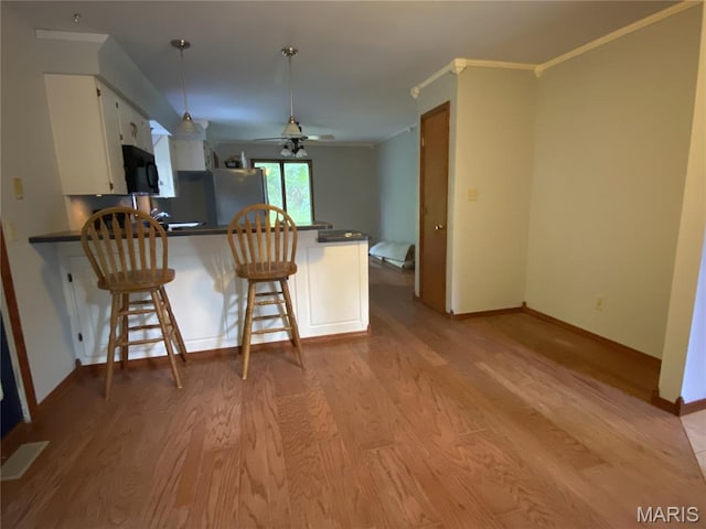 236 Mohawk Dr, Cape Girardeau, MO 63701 - kitchen featuring black microwave, a peninsula, dark countertops, light wood-style floors, and ceiling fan