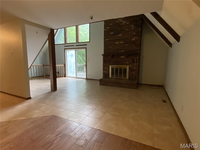 236 Mohawk Dr, Cape Girardeau, MO 63701 - unfurnished living room featuring baseboards, a brick fireplace, light tile patterned floors, and high vaulted ceiling