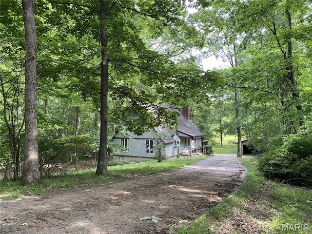 236 Mohawk Dr, Cape Girardeau, MO 63701 - view of home's exterior featuring a chimney, a forest view, a barn, asphalt driveway, and an outbuilding