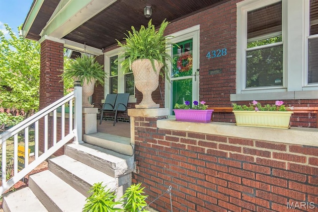 property entrance featuring a porch and brick siding