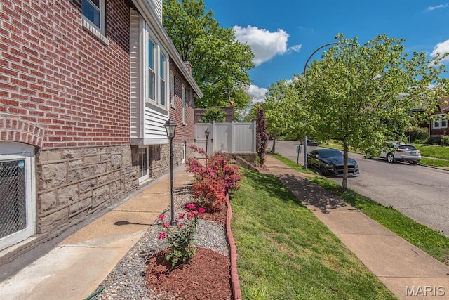 view of side of home featuring brick siding and fence