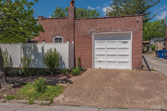 view of property exterior with concrete driveway, brick siding, fence, and a chimney