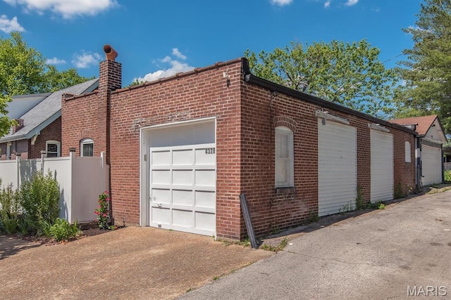 garage with fence and concrete driveway