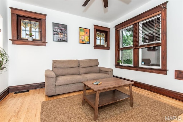 living area featuring baseboards, a ceiling fan, and light wood-style flooring