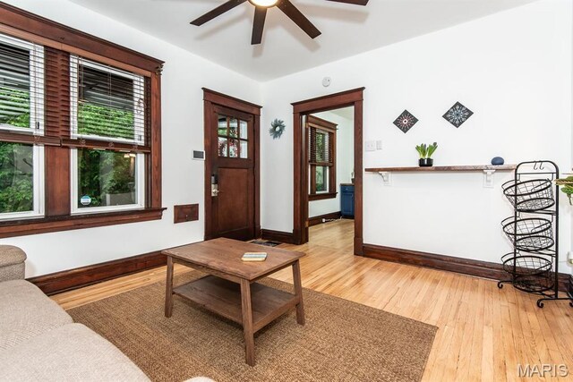 living area featuring light wood finished floors, baseboards, and ceiling fan