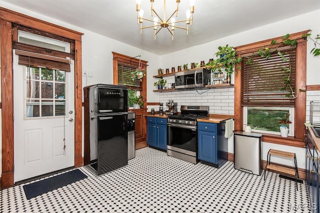 kitchen featuring blue cabinets, stainless steel appliances, butcher block counters, open shelves, and a chandelier