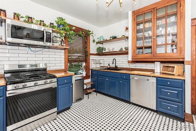 kitchen featuring stainless steel appliances, wood counters, open shelves, and blue cabinets