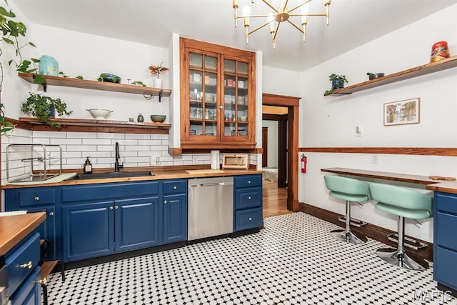 bar area with dishwasher, a sink, tasteful backsplash, a chandelier, and baseboards