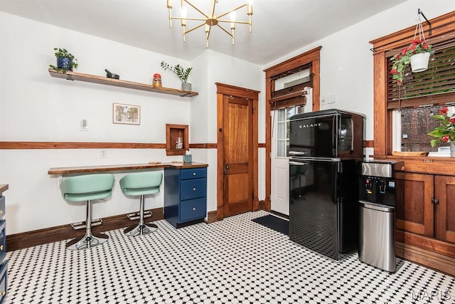 kitchen featuring freestanding refrigerator, open shelves, a chandelier, and light flooring