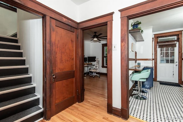 foyer entrance with stairway, light wood-type flooring, a ceiling fan, and baseboards