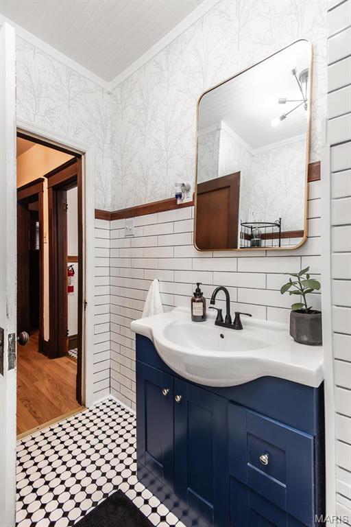 bathroom with ornamental molding, vanity, and tile walls
