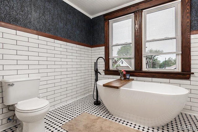 bathroom with tile walls, toilet, a freestanding bath, and ornamental molding