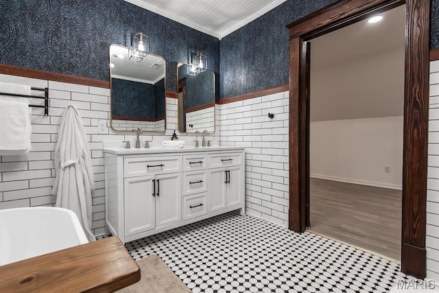 bathroom with tile walls, crown molding, double vanity, wainscoting, and a freestanding tub