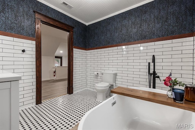 bathroom featuring tile walls, toilet, a soaking tub, and ornamental molding