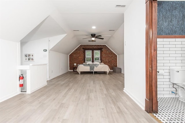 bonus room with light wood-style flooring, ceiling fan, brick wall, vaulted ceiling, and baseboards