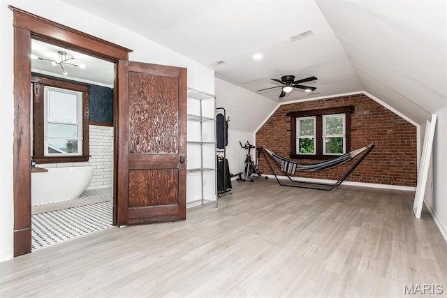 additional living space featuring brick wall, light wood-type flooring, vaulted ceiling, a ceiling fan, and baseboards