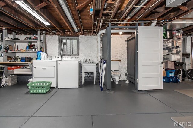 unfinished below grade area with washing machine and clothes dryer and a sink