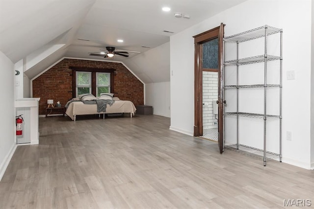 bedroom featuring light wood finished floors, baseboards, vaulted ceiling, brick wall, and ceiling fan