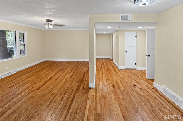 spare room with light wood finished floors, a ceiling fan, and baseboards