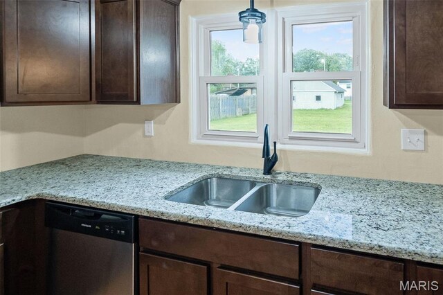 kitchen featuring stainless steel dishwasher, a sink, dark brown cabinetry, and light stone counters