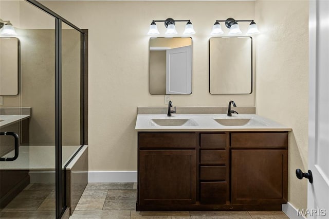 full bath featuring baseboards, double vanity, and a shower stall