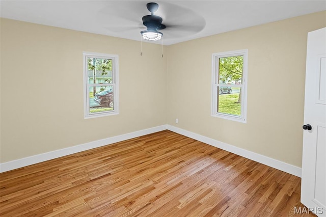unfurnished room with a ceiling fan, light wood-type flooring, and baseboards