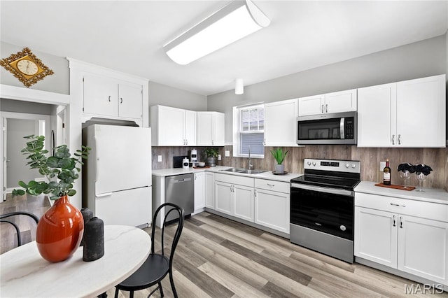 4020 Neosho St, Saint Louis, MO 63116 - kitchen with appliances with stainless steel finishes, a sink, backsplash, white cabinetry, and light countertops