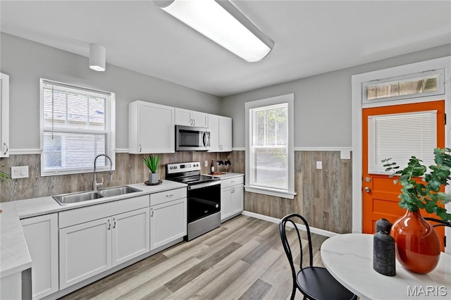 4020 Neosho St, Saint Louis, MO 63116 - kitchen featuring appliances with stainless steel finishes, a sink, white cabinets, light countertops, and wainscoting