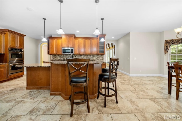 1019 Hawks Landing Dr, Lake St Louis, MO 63367 - kitchen featuring appliances with stainless steel finishes, baseboards, tasteful backsplash, dark stone counters, and brown cabinets