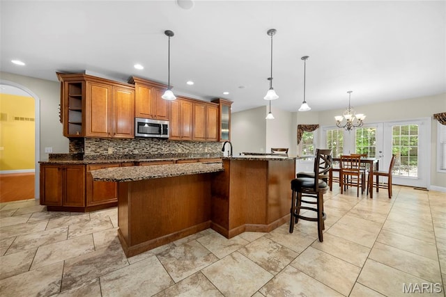 1019 Hawks Landing Dr, Lake St Louis, MO 63367 - kitchen with stainless steel microwave, brown cabinetry, backsplash, dark stone counters, and recessed lighting
