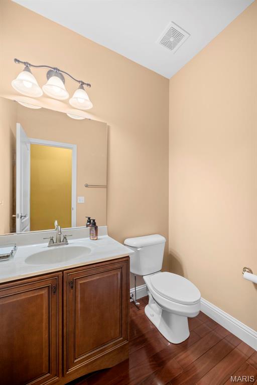 1019 Hawks Landing Dr, Lake St Louis, MO 63367 - half bathroom featuring toilet, vanity, wood finished floors, and baseboards