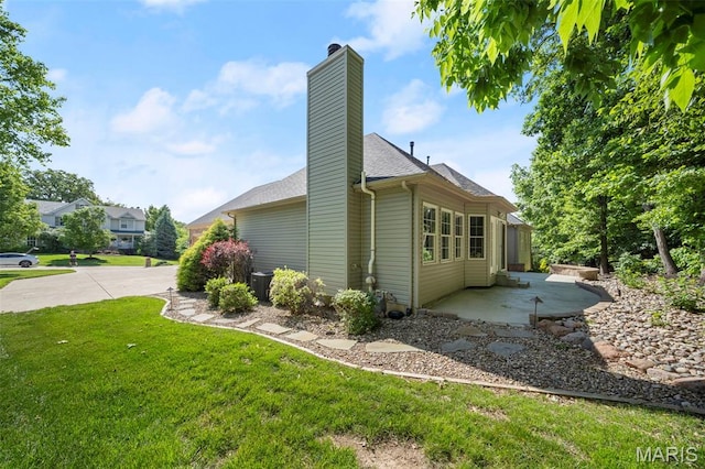 1019 Hawks Landing Dr, Lake St Louis, MO 63367 - view of property exterior featuring a lawn, a patio, a chimney, and roof with shingles