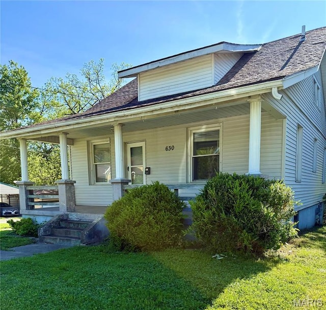 bungalow-style house with a porch, a front yard, and roof with shingles