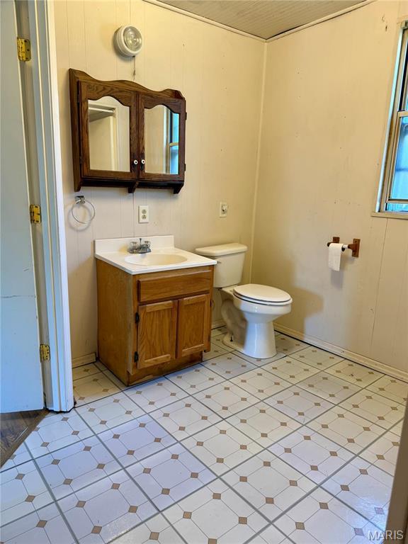 half bathroom featuring toilet, vanity, and tile patterned floors