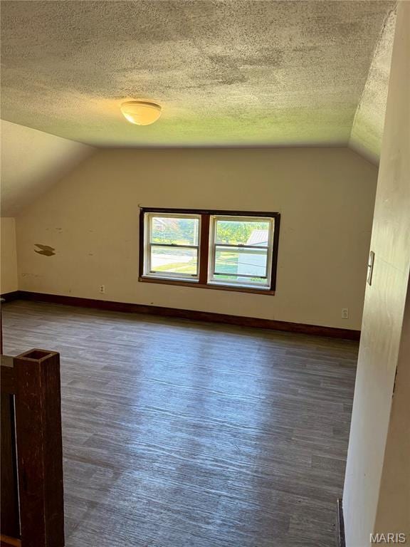 bonus room with vaulted ceiling, a textured ceiling, wood finished floors, and baseboards