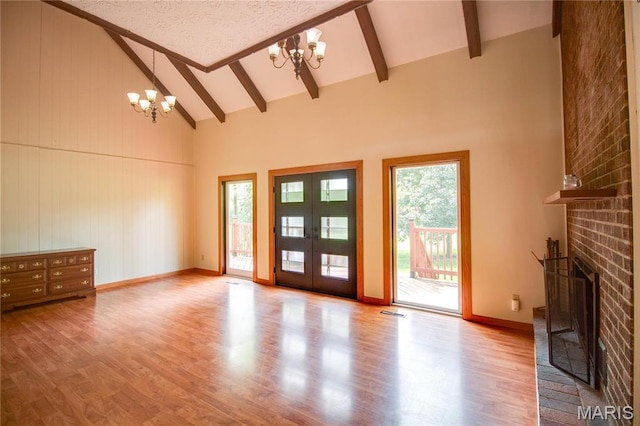 968 Super Slab Rd, Greenfield, IL 62044 - unfurnished living room with a chandelier, wood finished floors, high vaulted ceiling, beam ceiling, and a brick fireplace