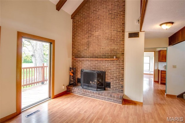 968 Super Slab Rd, Greenfield, IL 62044 - unfurnished living room with wood finished floors, beam ceiling, baseboards, a brick fireplace, and high vaulted ceiling