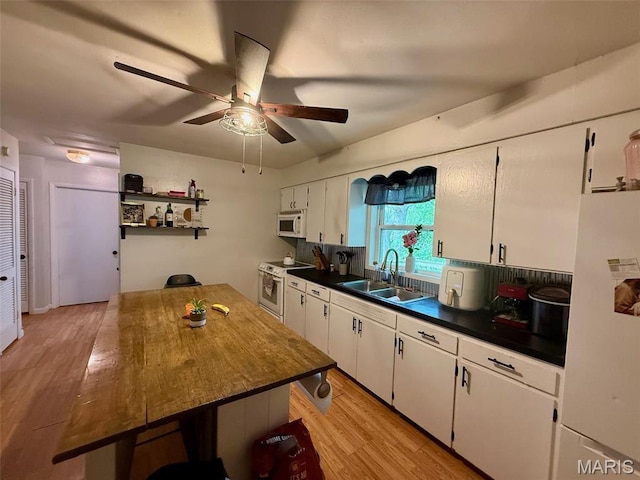 kitchen with white appliances, a sink, a ceiling fan, white cabinets, and light wood-type flooring