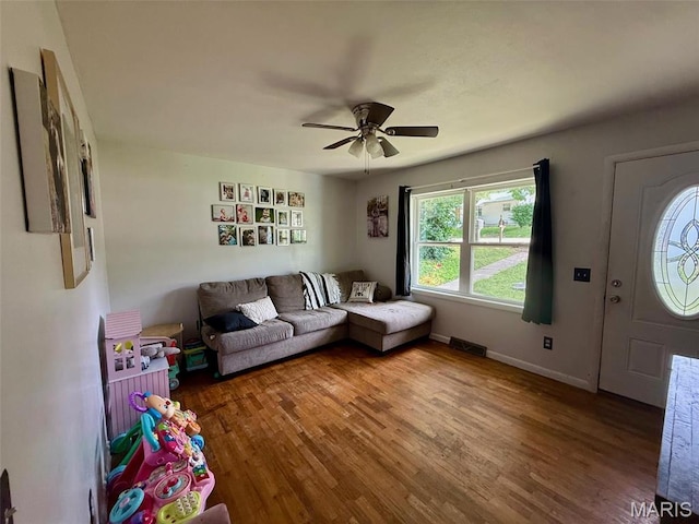 living area featuring wood finished floors, a ceiling fan, and baseboards
