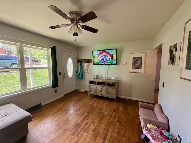 living area featuring wood finished floors, baseboards, and a ceiling fan
