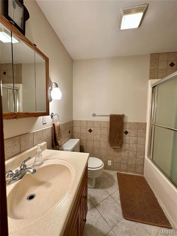 15716 County Road 5190, Rolla, MO 65401 - bathroom featuring tile walls, wainscoting, toilet, tile patterned floors, and combined bath / shower with glass door