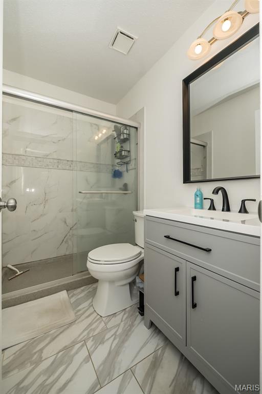 101 Holly Green Dr, Ballwin, MO 63021 - bathroom with marble look tiles, toilet, a shower stall, and vanity