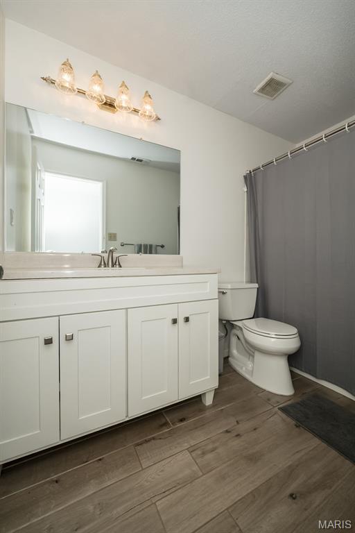 101 Holly Green Dr, Ballwin, MO 63021 - bathroom with wood finished floors, toilet, and vanity