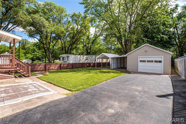 106 E Ofallon Dr, Caseyville, IL 62232 - view of yard with a detached garage, asphalt driveway, an outdoor structure, and view of wooded area