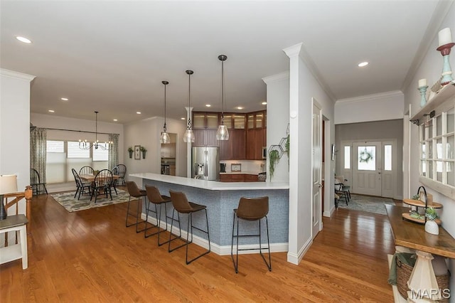 1804 Sterling Oaks Dr, Saint Peters, MO 63376 - kitchen featuring stainless steel fridge with ice dispenser, a peninsula, a kitchen bar, light countertops, and ornamental molding