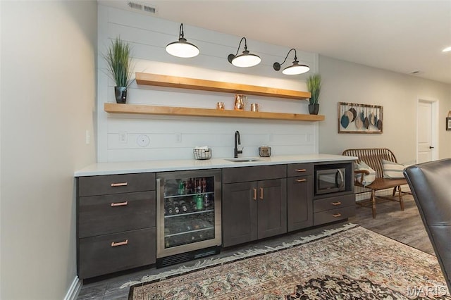 1804 Sterling Oaks Dr, Saint Peters, MO 63376 - indoor wet bar featuring wine cooler, dark wood-type flooring, stainless steel microwave, and baseboards