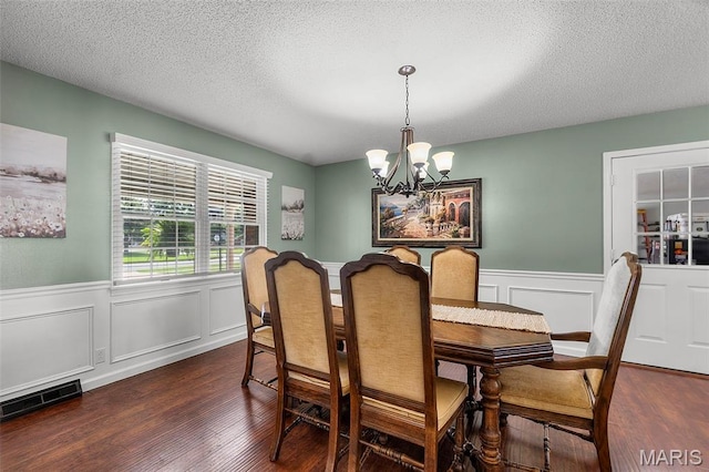 729 Euclid Dr, Sikeston, MO 63801 - dining room featuring a chandelier, dark wood finished floors, wainscoting, a textured ceiling, and a decorative wall
