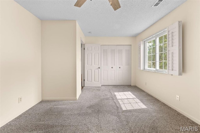 unfurnished bedroom with carpet flooring, a textured ceiling, baseboards, and a closet
