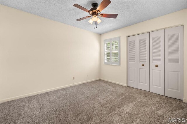 unfurnished bedroom featuring carpet floors, a textured ceiling, baseboards, a closet, and a ceiling fan