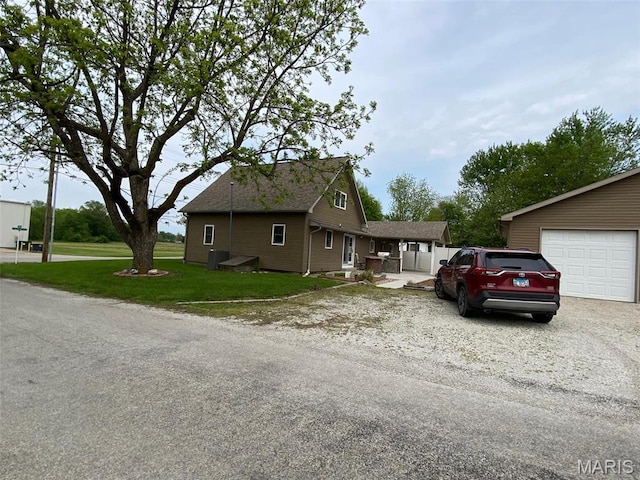 bungalow-style home featuring a front yard, driveway, central AC unit, and a garage